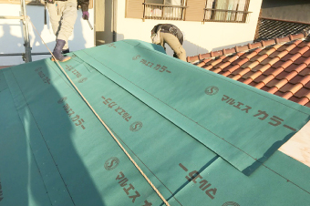 野地板の上に防水紙を敷く様子